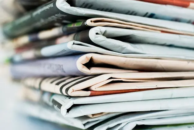 A photo of a stack of folded newspapers conveying a large number of articles